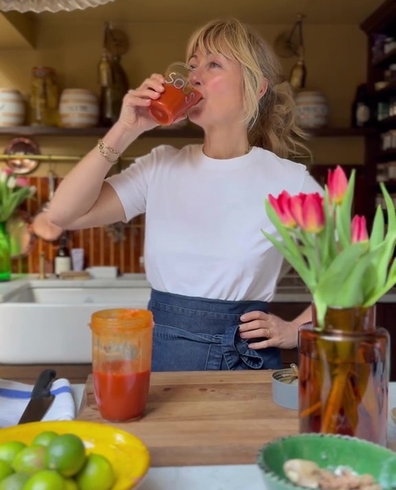 Woman drinking juice in kitchen.