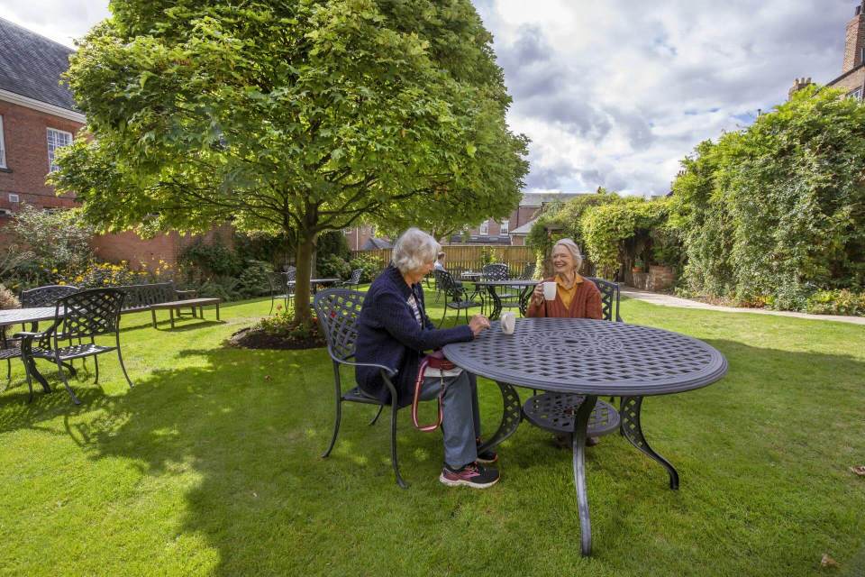 Two women enjoying coffee together at an outdoor cafe table.