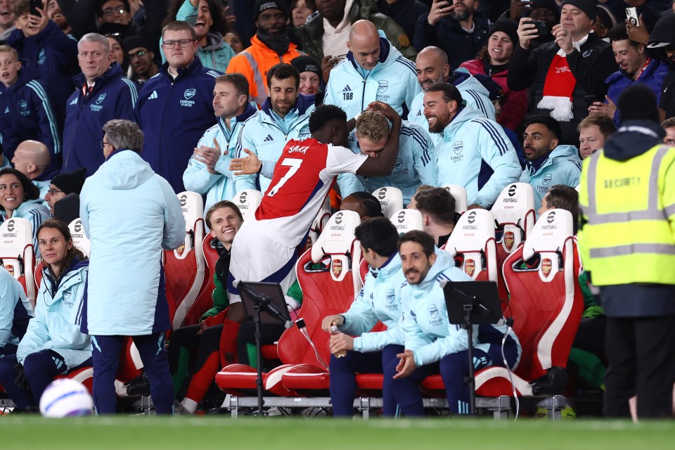 Bukayo Saka of Arsenal celebrates a goal with teammates and coaches.