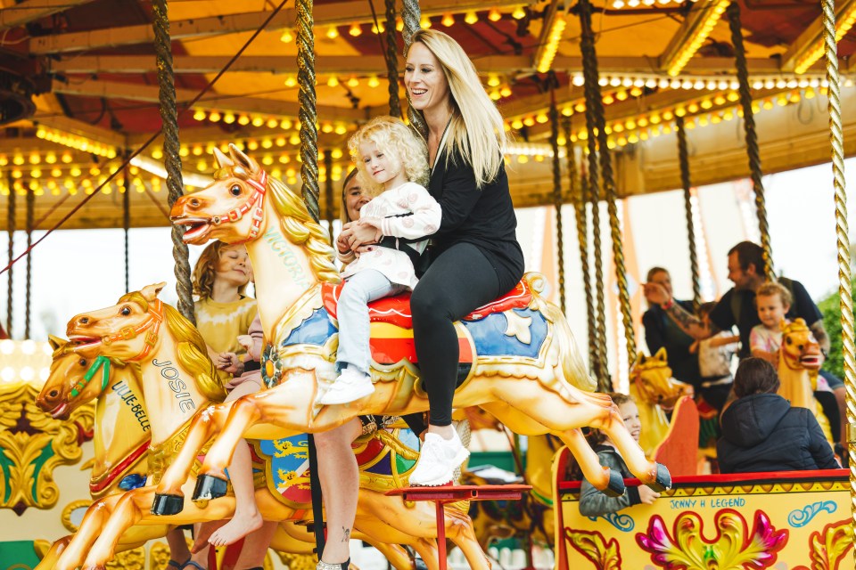 A woman and child riding a carousel horse.