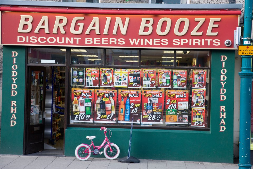 Bargain Booze off-license shop exterior with window displays advertising alcohol deals.