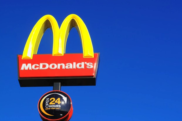 McDonald's logo and 24-hour drive-thru sign against a blue sky.
