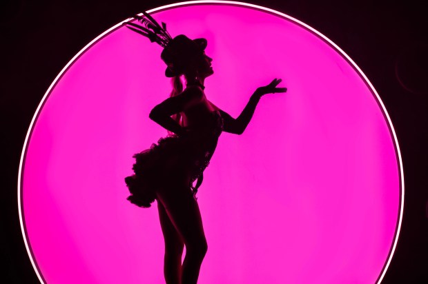 Silhouette of a showgirl in front of a pink background.