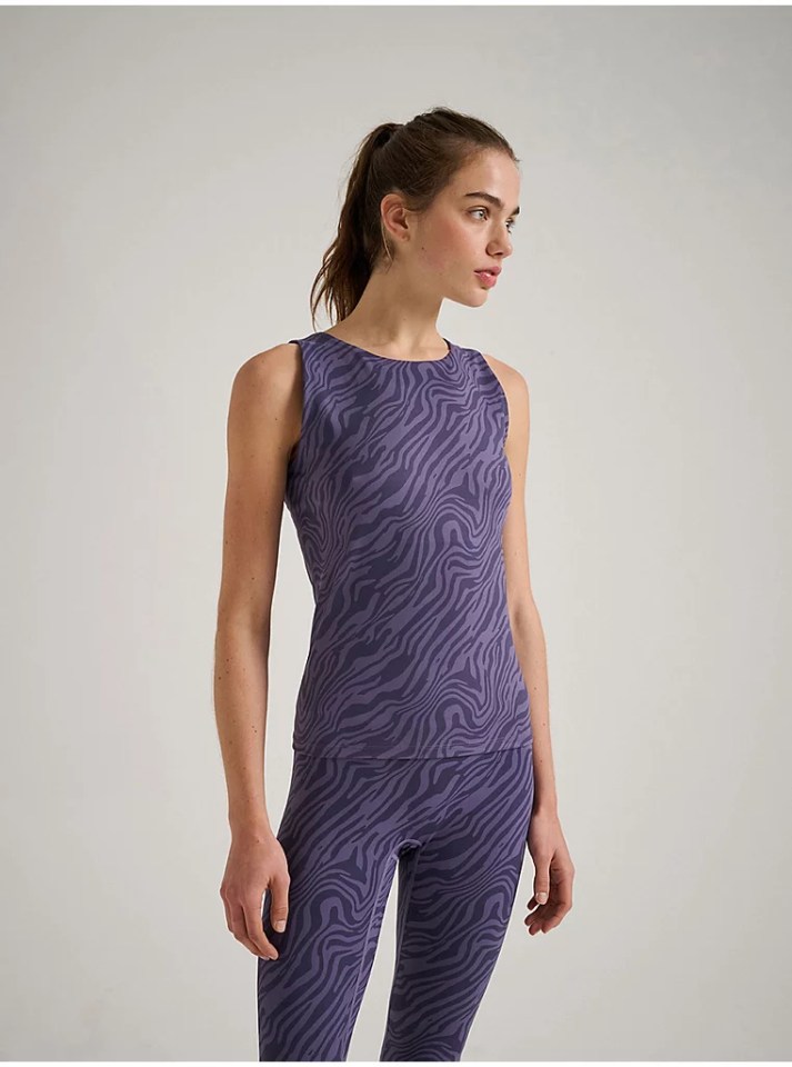 Woman wearing purple zebra-striped tank top and leggings.