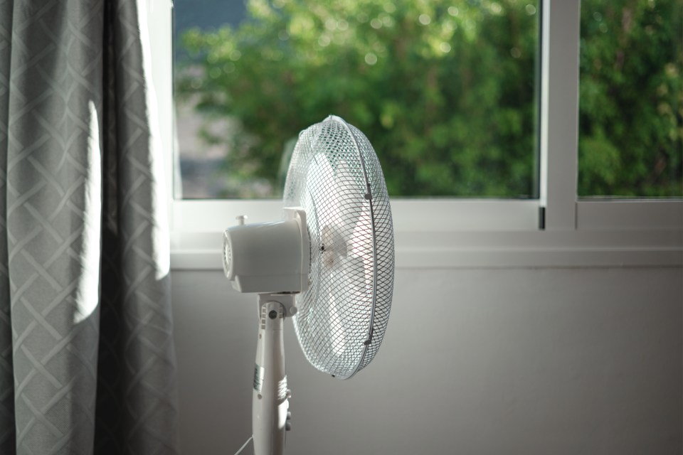 Electric stand fan in a bedroom.