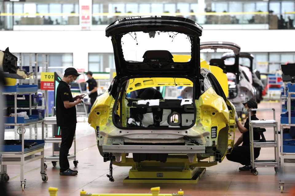 Workers assembling an electric SUV on a factory assembly line.