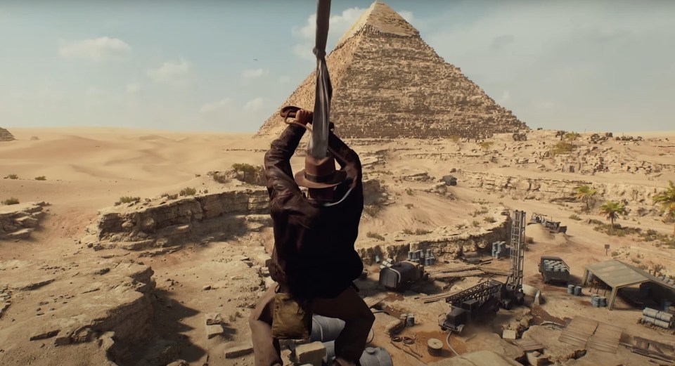 Indiana Jones swinging from a rope in front of a pyramid.