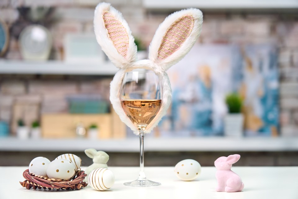Wine glass with bunny ears, Easter eggs, and small bunny figurines.