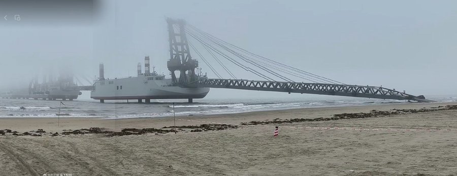 Large crane ship on the beach in foggy conditions.