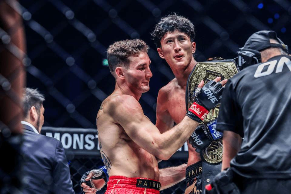 Two MMA fighters holding a championship belt.