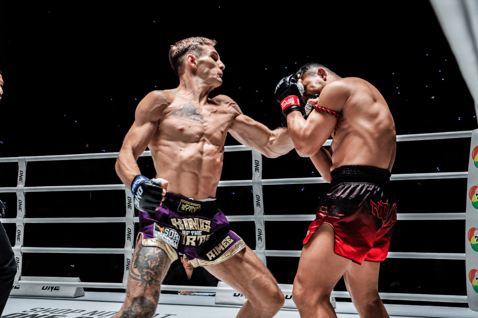Two Muay Thai fighters in a boxing ring exchanging blows.