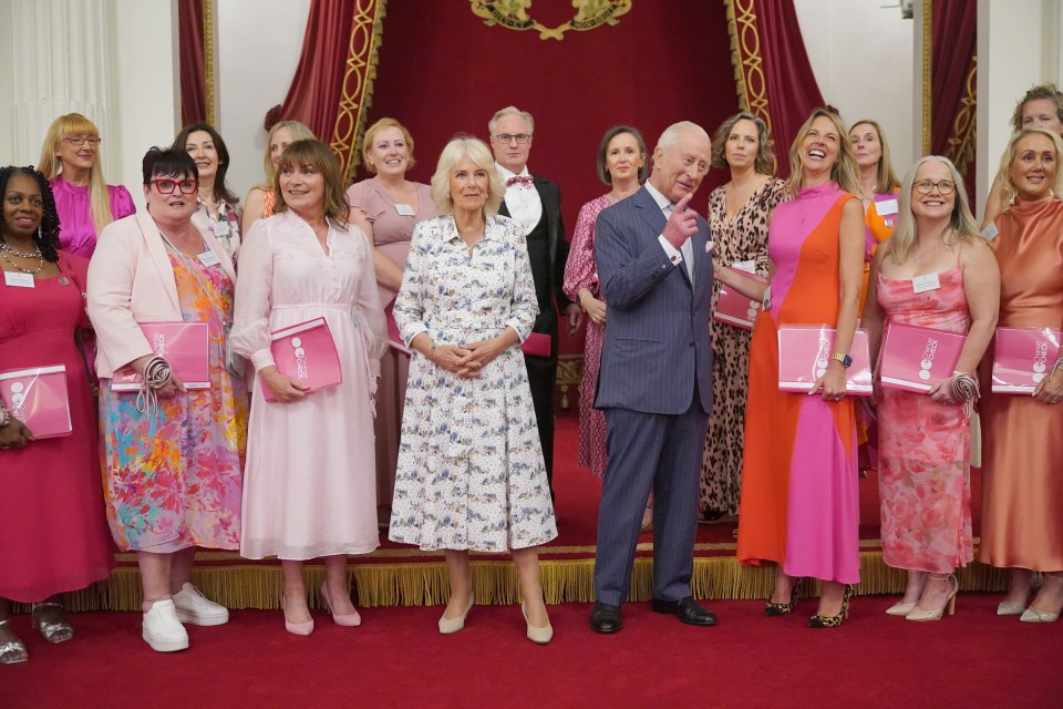 King Charles III and Queen Camilla with attendees at a Buckingham Palace reception celebrating cancer awareness initiatives.
