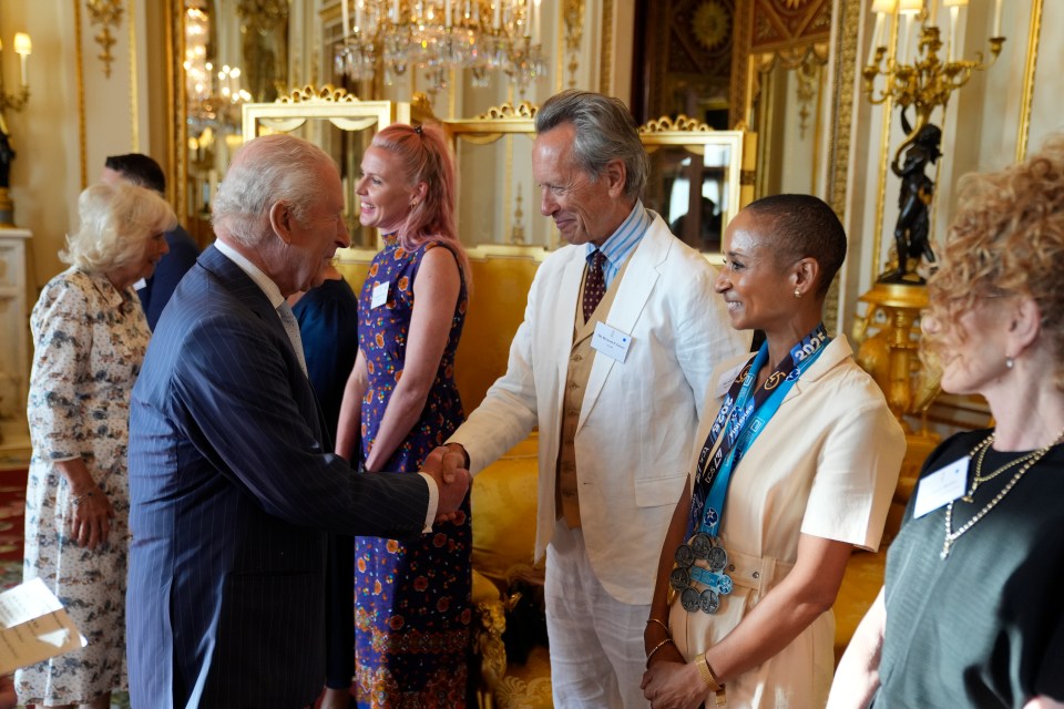 King Charles III shaking hands with Richard E Grant at a Buckingham Palace reception.