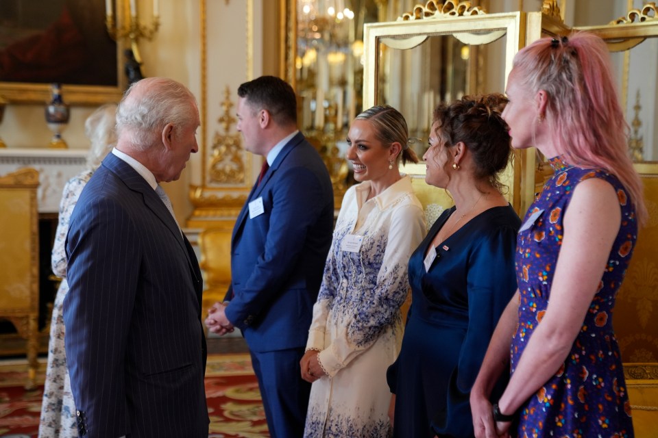 King Charles III speaking with several women at a Buckingham Palace reception.