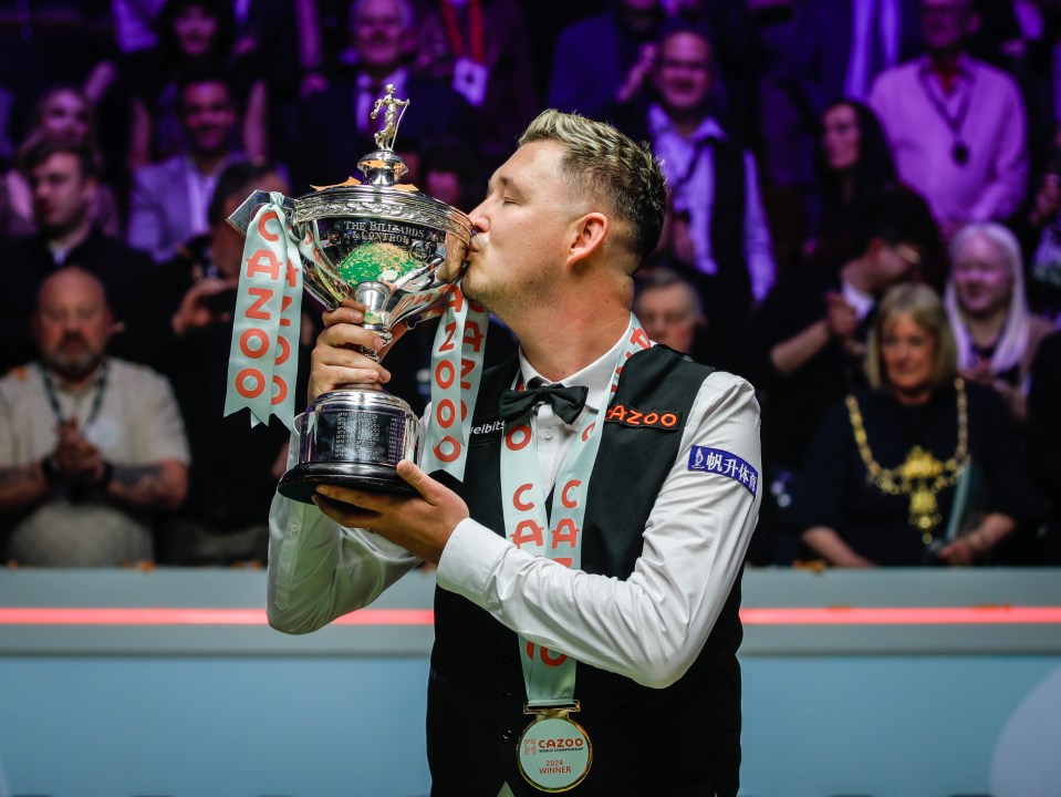 Kyren Wilson kissing the World Snooker Championship trophy.