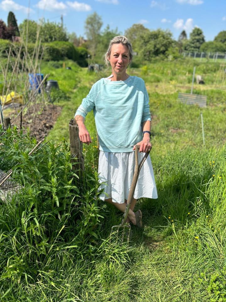 Woman standing in a garden with a garden fork.