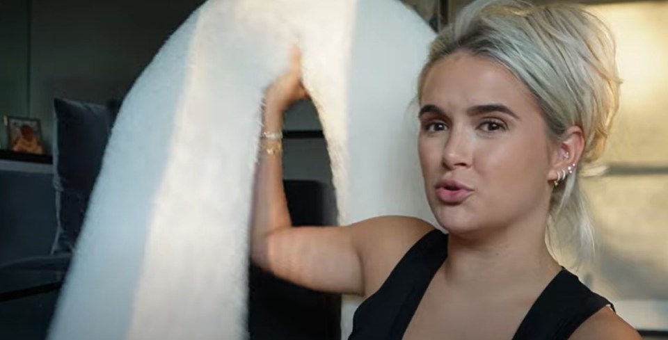 Woman holding up a white fluffy blanket.