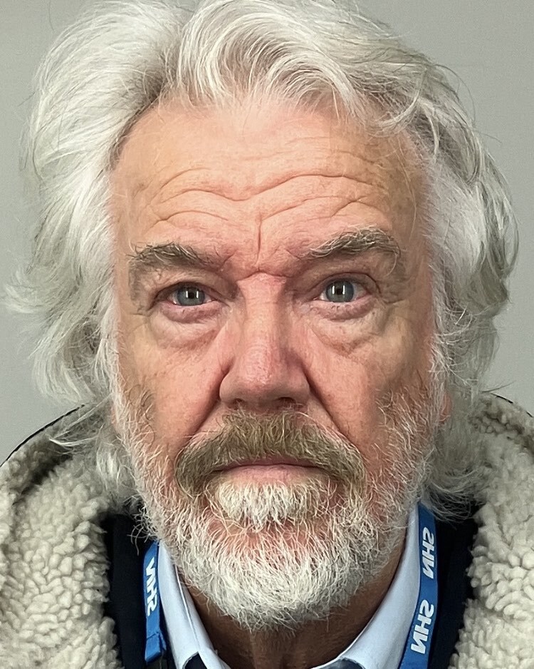 Headshot of an older man with long gray hair and a gray beard.