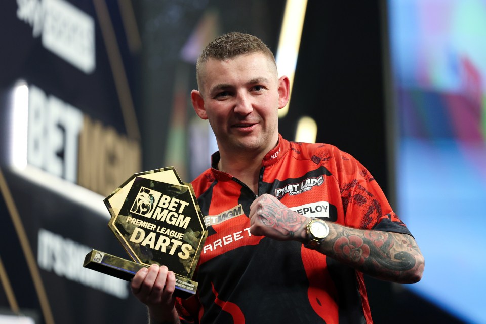 Nathan Aspinall holding the BetMGM Premier League Darts trophy.