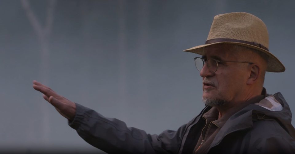 Man in hat gesturing.
