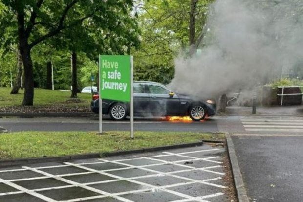 An image collage containing 1 images, Image 1 shows Car on fire in a parking lot near a "Have a safe journey" sign