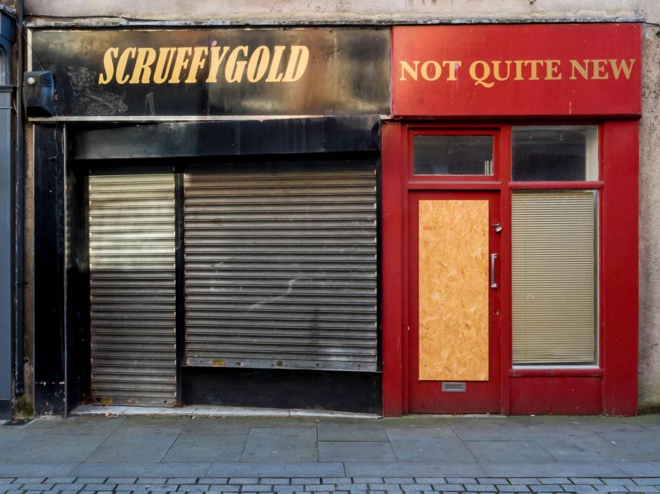 Two closed-down shops in Bishop Auckland, UK.  One shop's sign reads "Scruffygold," the other "Not Quite New."