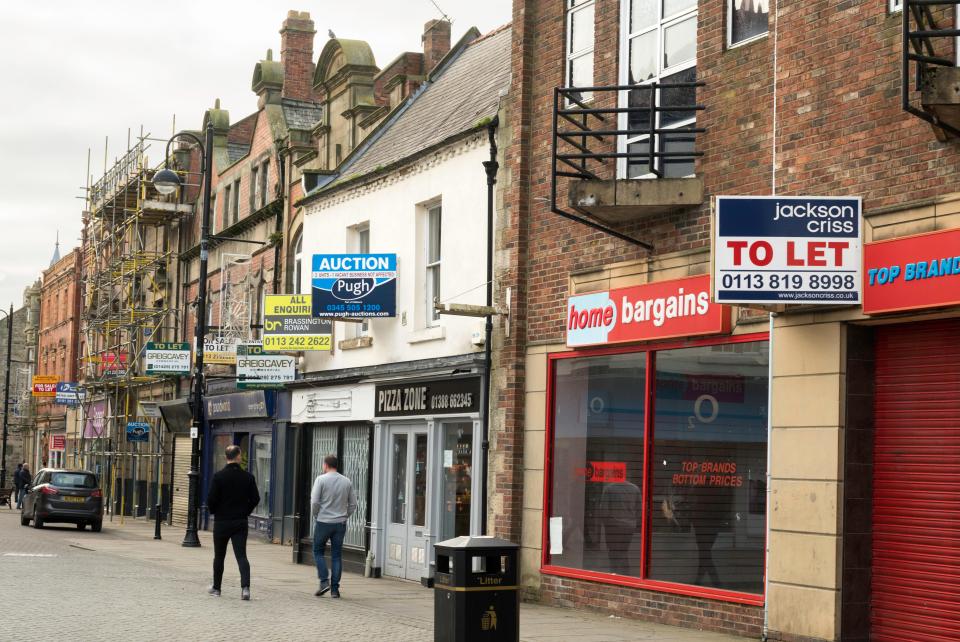 Row of empty shops with "To Let" and "For Sale" signs.