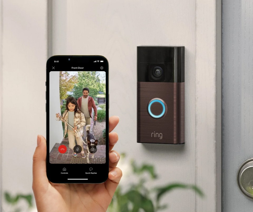 Smartphone displaying a Ring doorbell video feed of a family and their dog at the front door.
