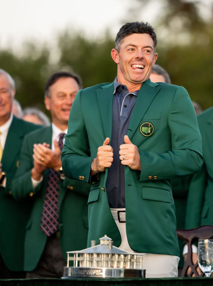 Rory McIlroy smiling and putting on his green jacket at the Masters Tournament.