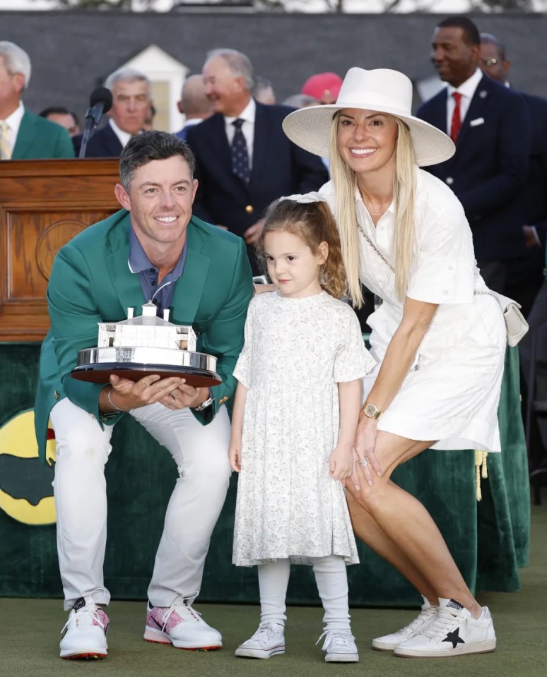 Rory McIlroy holding a trophy with his wife and daughter.