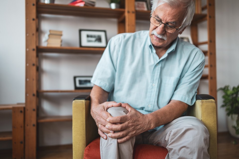 Senior man holding his knee in pain.