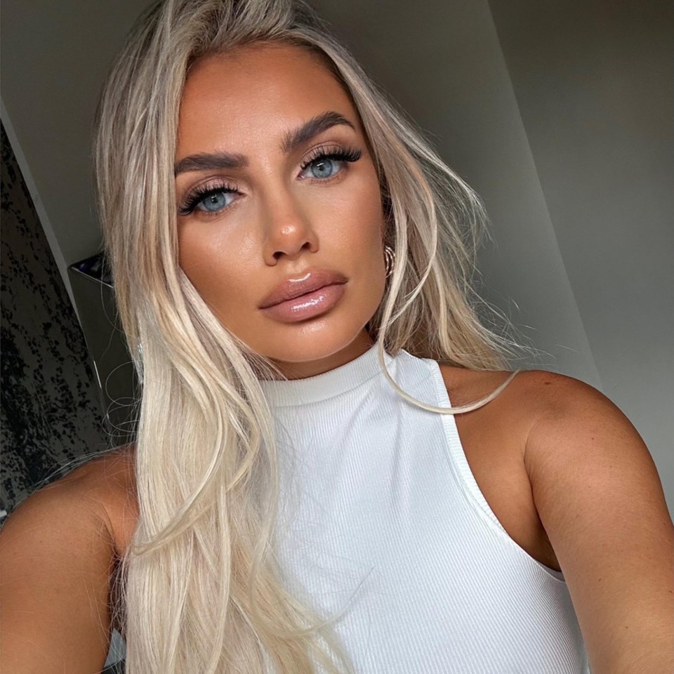 Woman with long blonde hair wearing a white top.