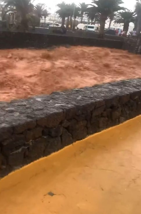 Floodwaters overflowing a low stone wall.