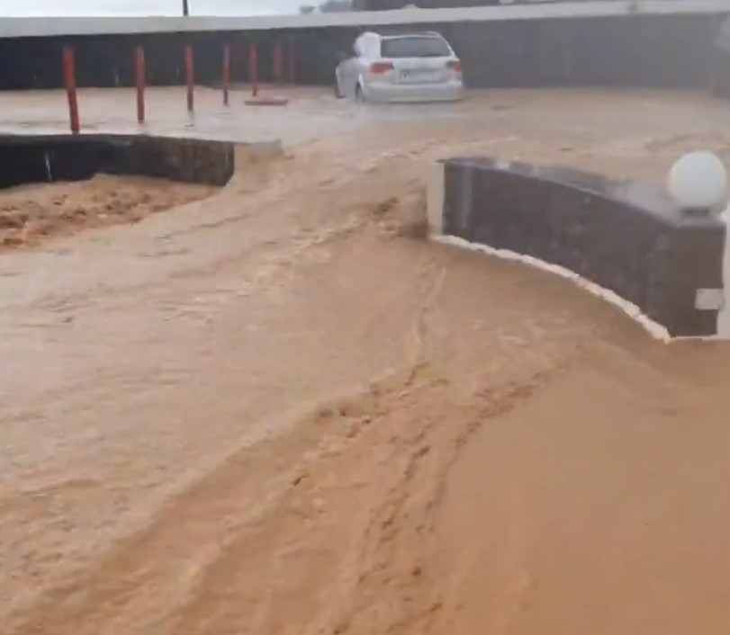 Flooded parking lot with a car driving through.