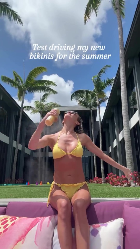 Woman in yellow bikini spraying sunscreen outdoors.