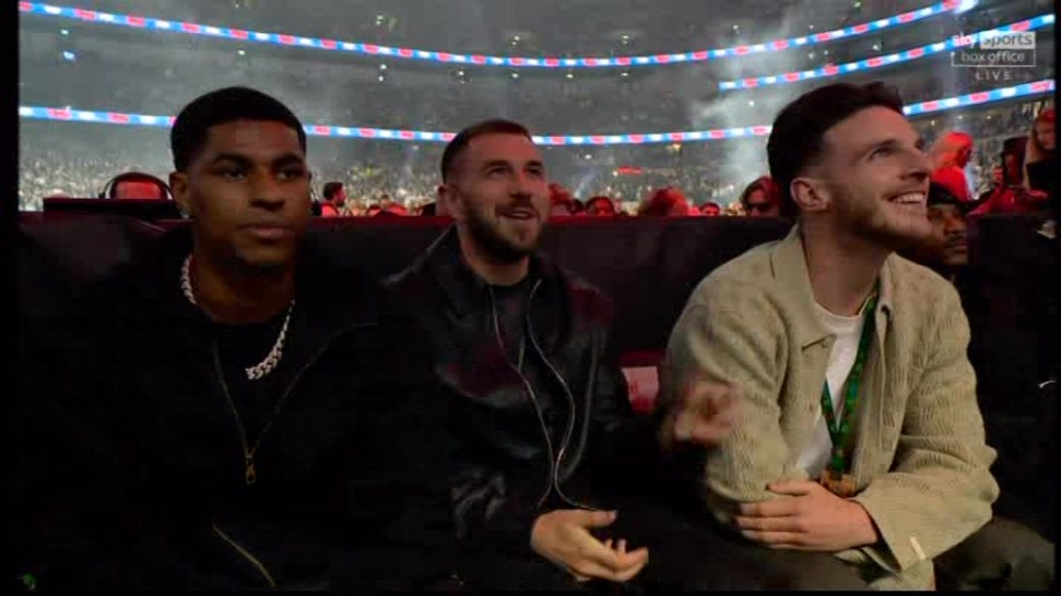 Three men sitting together in a stadium.