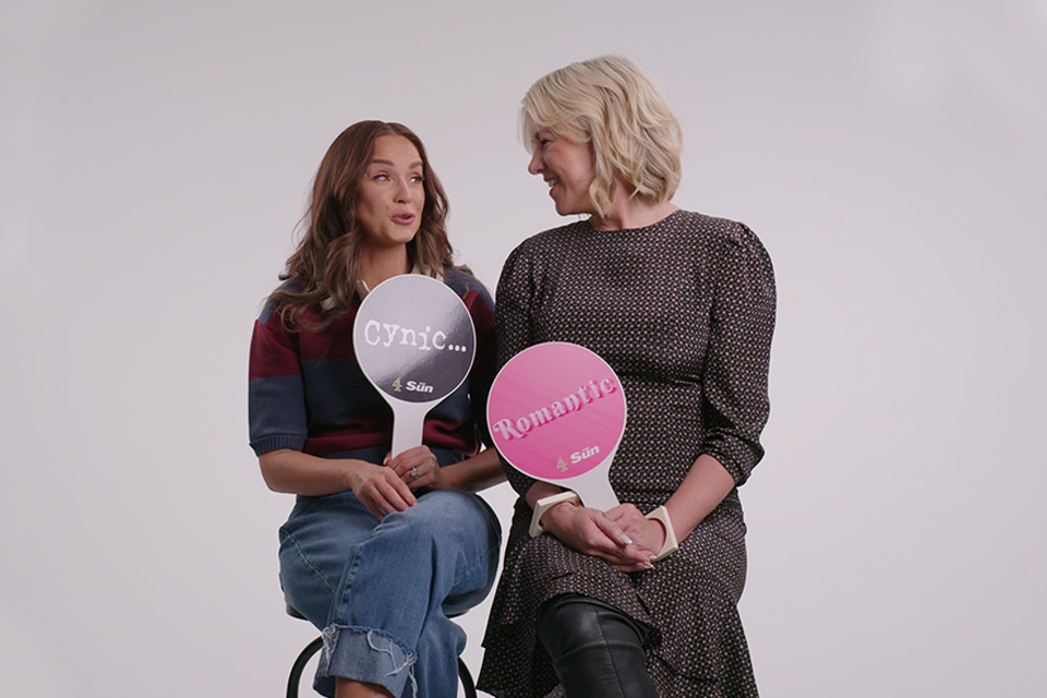 Two women holding signs that say "Cynic..." and "Romantic".