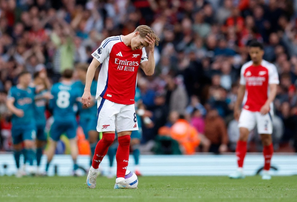 Martin Odegaard looking dejected on a soccer field.