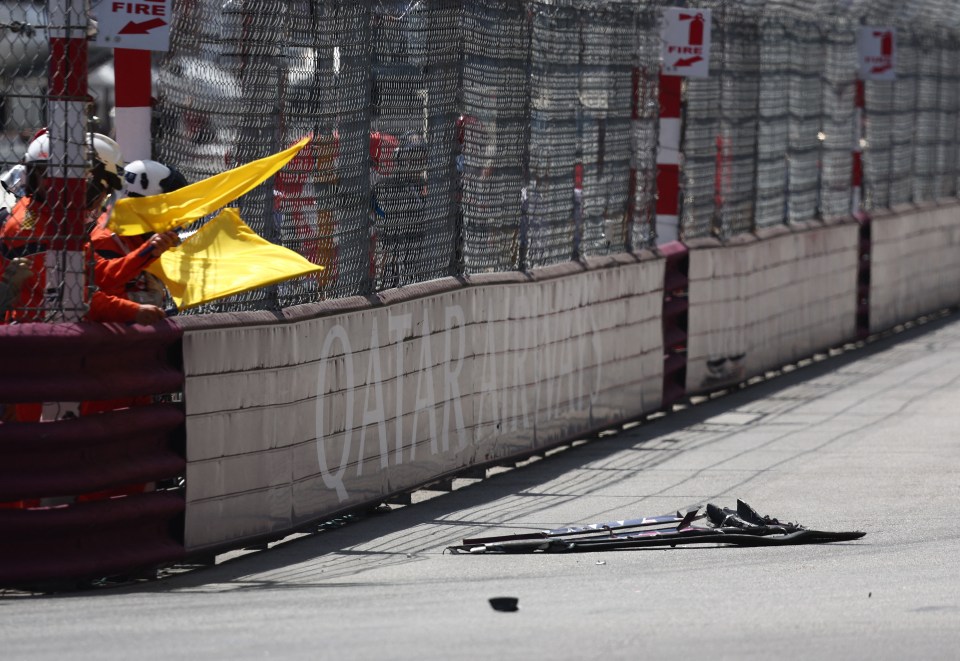 Debris on a racetrack with a yellow flag being waved.