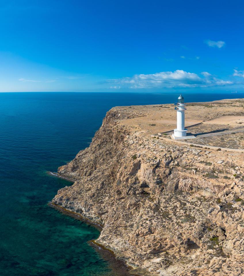 Aerial view of a lighthouse on a cliff overlooking the sea.