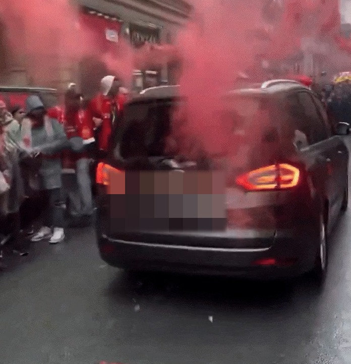 Car driving through a crowd emitting red smoke.