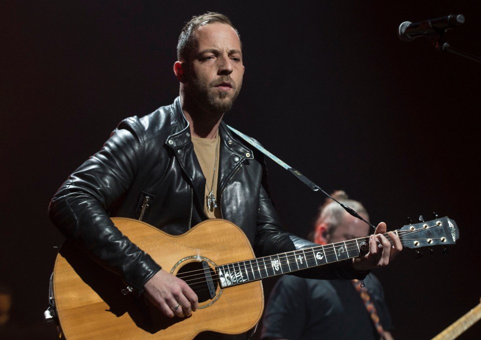 James Morrison performing at a concert, playing an acoustic guitar.