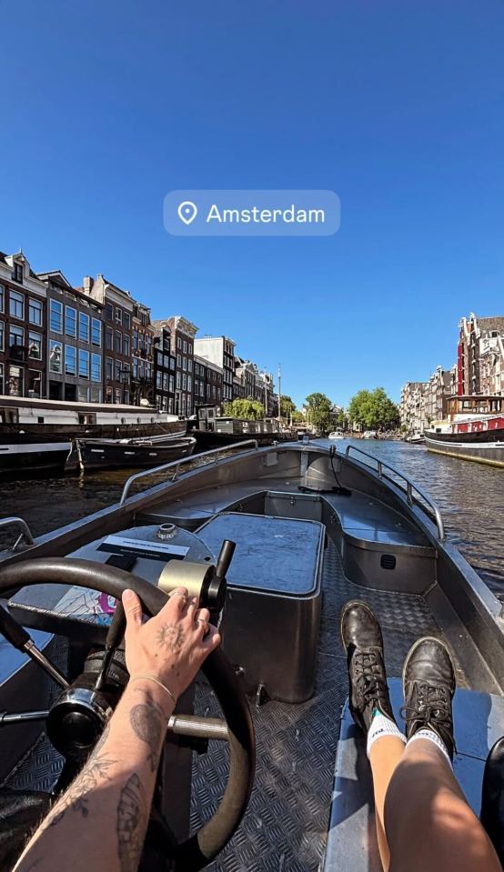 Person steering a boat on a canal in Amsterdam.
