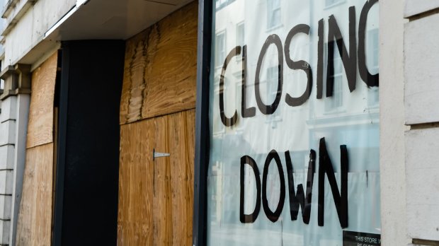 Boarded-up shop window with a "Closing Down" sign.