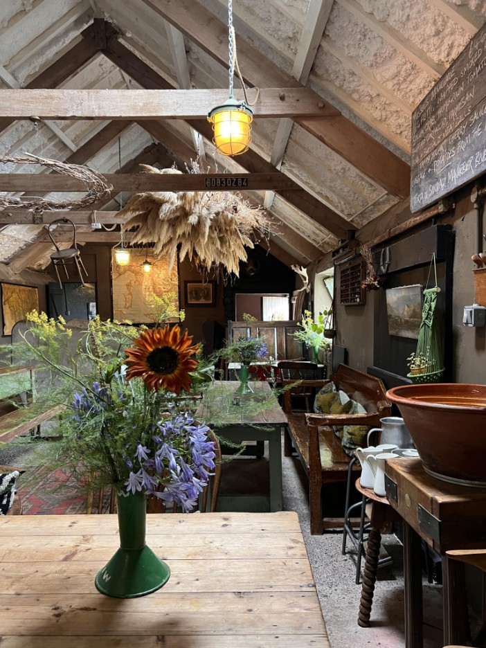 Rustic interior with wooden beams, hanging dried flowers, and a sunflower bouquet.