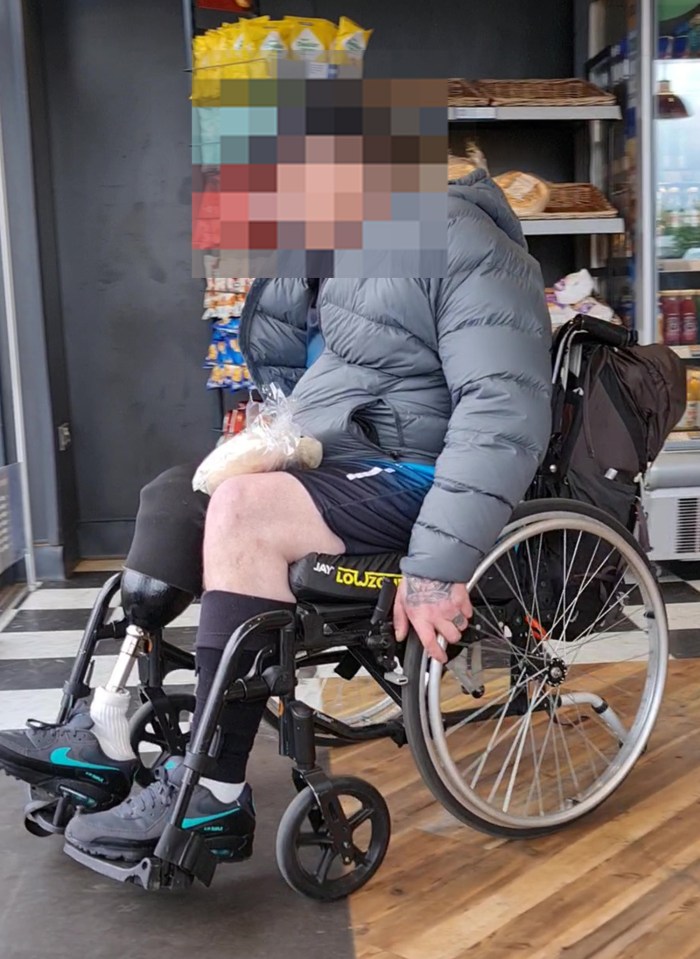 Person with a prosthetic leg sitting in a wheelchair in a shop.