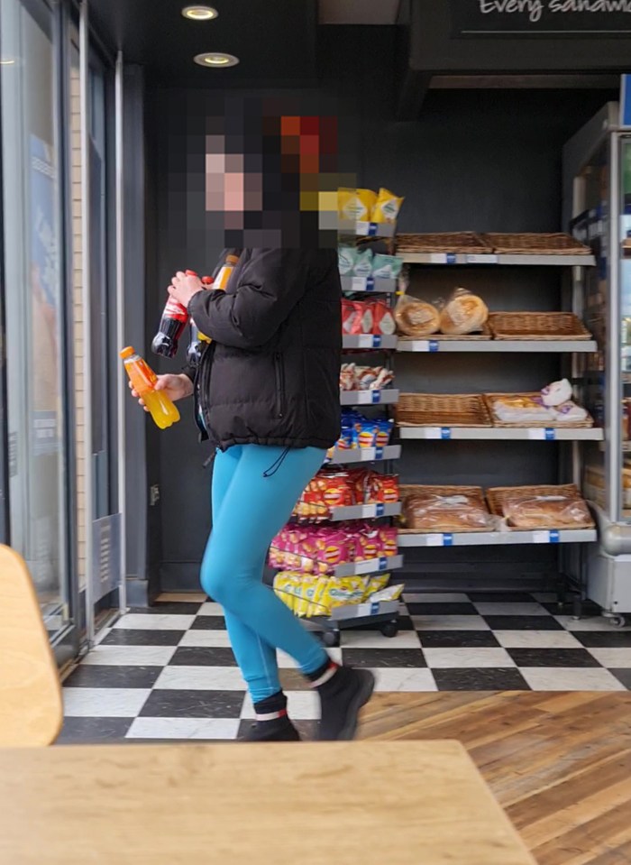 Person in blue leggings holding drinks in a shop.
