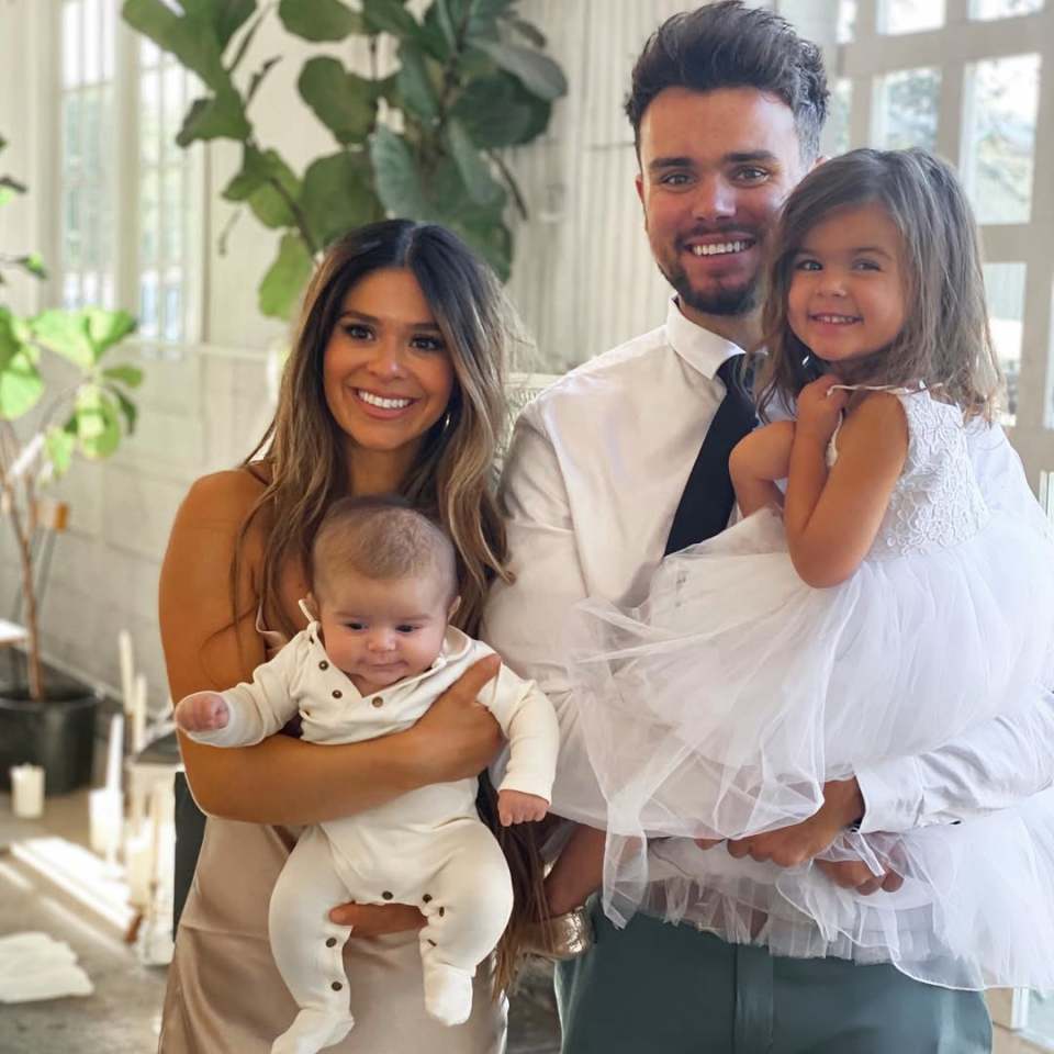 Family portrait of parents holding their infant and toddler.
