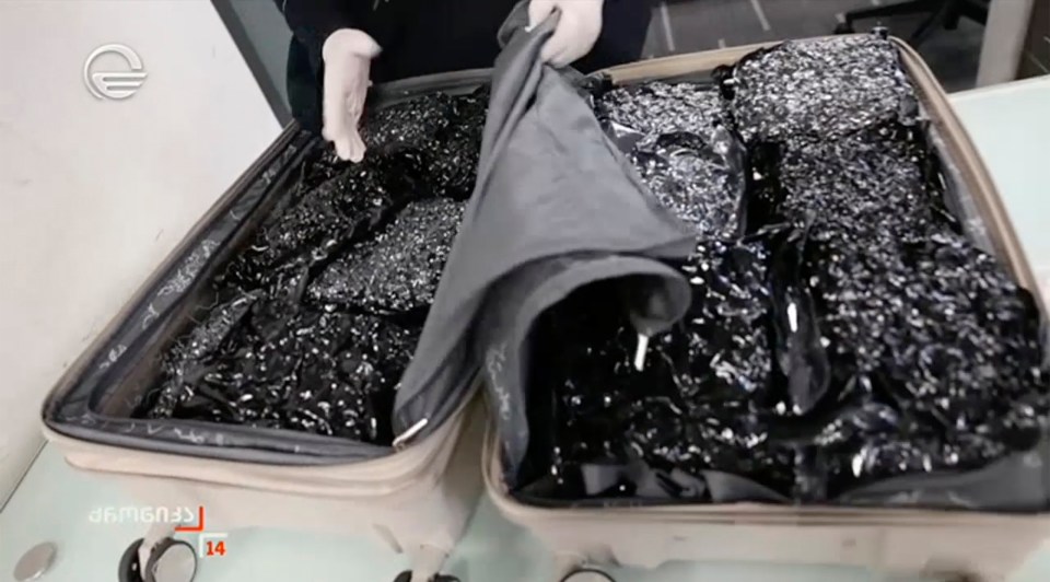 Suitcase filled with black packages.