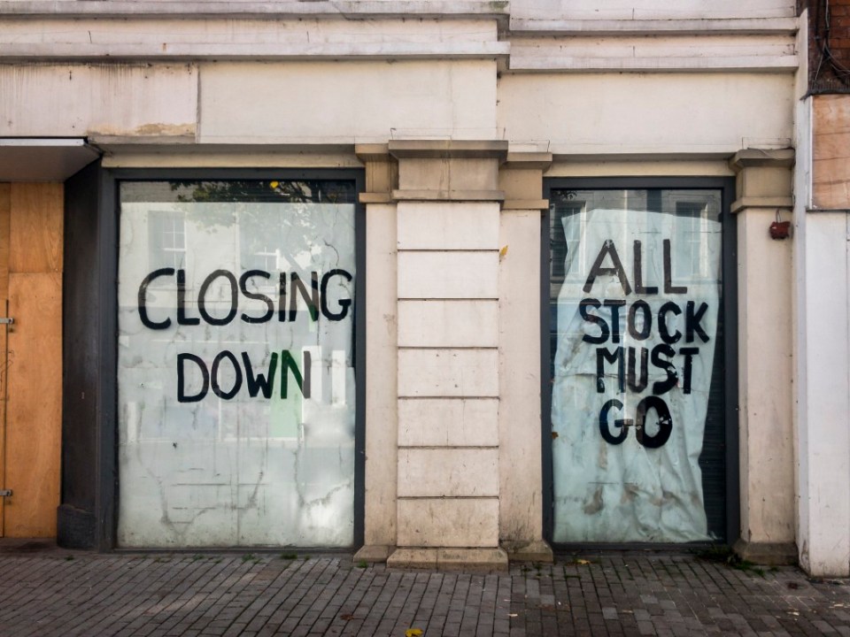 Closed shop windows with signs reading "Closing Down" and "All Stock Must Go."